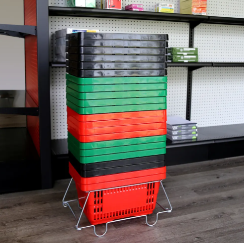 A stack of plastic storage bins in black, green, and red, held upright on a small metal wire stand in a retail or storage room setting with shelving in the background.