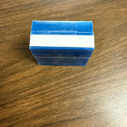 A small rectangular blue item with a white horizontal band across the middle, photographed on a brown wood-grain surface.