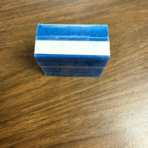 A small rectangular blue item with a white horizontal band across the middle, photographed on a brown wood-grain surface.