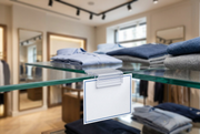 Flip-up sign holder on a glass retail shelf