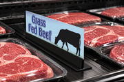 Illustrative Grass Fed Beef 4 x 12 inch meat case divider with cow artwork and slim sign in a low-profile black holder, displayed among meat trays