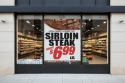 Custom printed price and item supermarket window poster hung in a grocery store storefront window, readable from the sidewalk