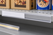 Clear 48-inch adhesive C-channel price rail installed on a grocery gondola shelf edge with a white price insert partly slid into the channel