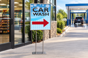 Car Wash right-arrow 22 × 28-inch poster with black lettering and blue bubble background displayed in a floor stand near a convenience store entrance.