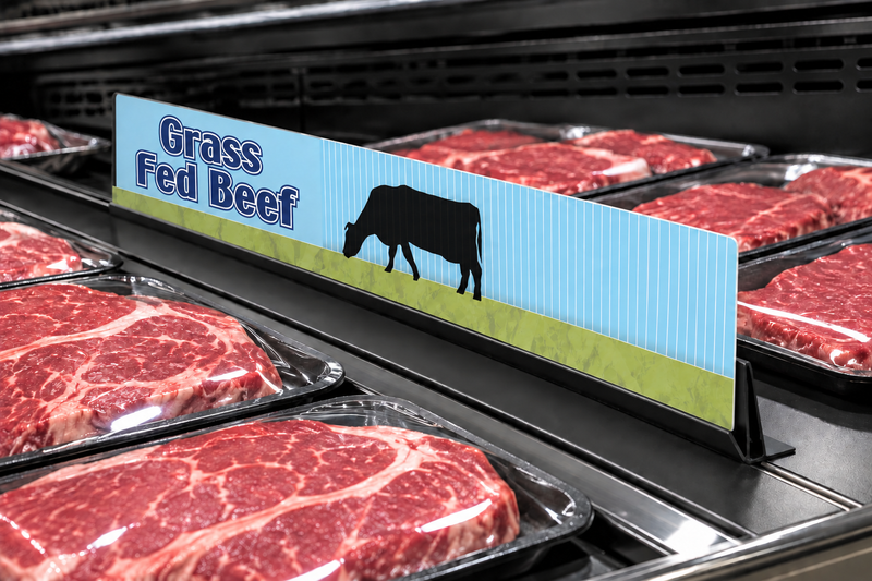 Illustrative Grass Fed Beef 24-inch meat case divider with a visibly thin printed sign panel in a low-profile black holder among meat trays