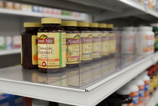 Thin clear PVC shelf dividers with adhesive bases separating vitamin bottles into organized lanes on a retail shelf.
