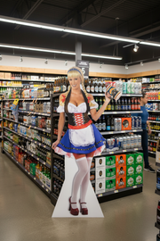 Custom-printed life-size floor standee displayed inside a beer and spirits retail store, positioned near beer shelves as a point-of-sale display.