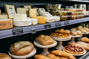 Black reusable write-on/wipe-off price tags displayed in individual sign holders beside deli foods and bakery products