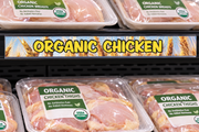 Organic Chicken price channel molding strip with wheat field artwork installed on a meat department shelf edge above packaged organic chicken