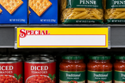 Red SPECIAL lettering on a long yellow 11 by 2.5 inch coated cardstock shelf sign displayed in holders on a supermarket shelf