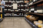 Satin nickel 42-inch metal floor sign holder with down-position clip displayed in a wine shop aisle