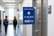 Custom printed blue Teacher of the Month school door sign hanging from a hook bracket over a classroom door, 11x17 card stock, SKU MSHSSG