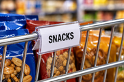 Clear curved snap-on label holder with a paper insert mounted on the front wire of a retail snack basket.