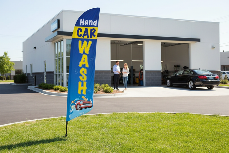Hand Car Wash feather flag installed in green grass beside an automotive wash bay, showing the outdoor roadside advertising use case