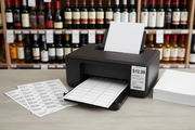 Printable wine-shop price-tag sheets beside a printer